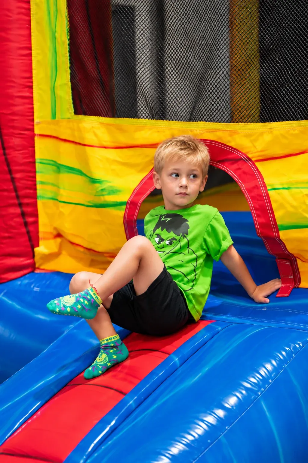 A child in colorful grip socks sitting at the bounce-house entrance.
