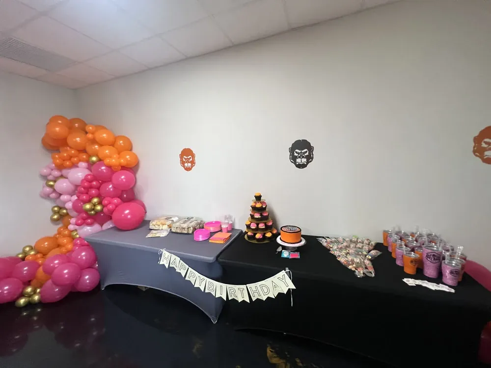 Fort Rock’s party room set for a birthday: balloon garland, black-draped tables, a Fort Rock cake and cupcakes under the gorilla decals