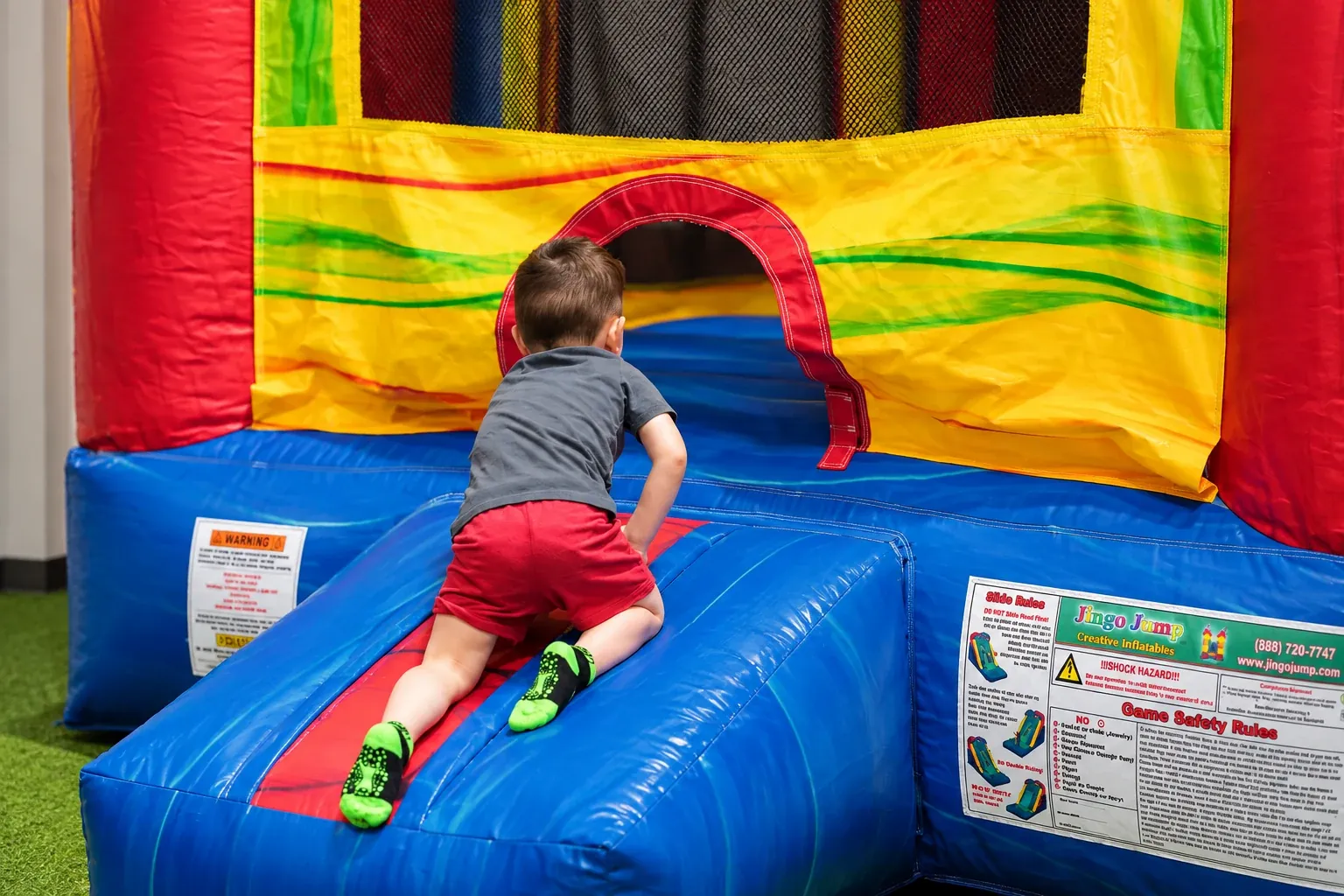 A child wearing grip socks entering Fort Rock’s inflatable bounce house.