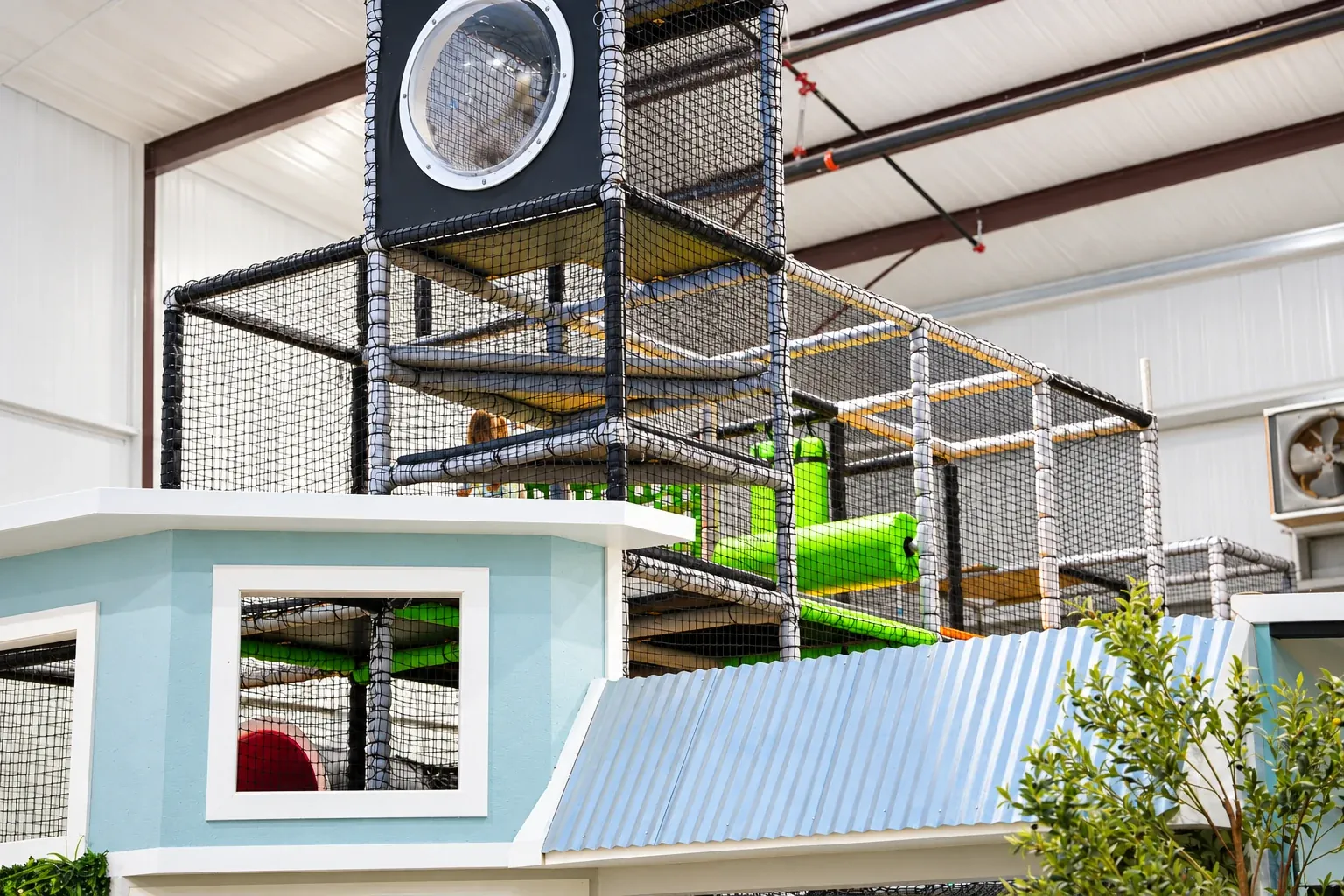 Fort Rock’s multilevel play structure with netted platforms and green play elements.